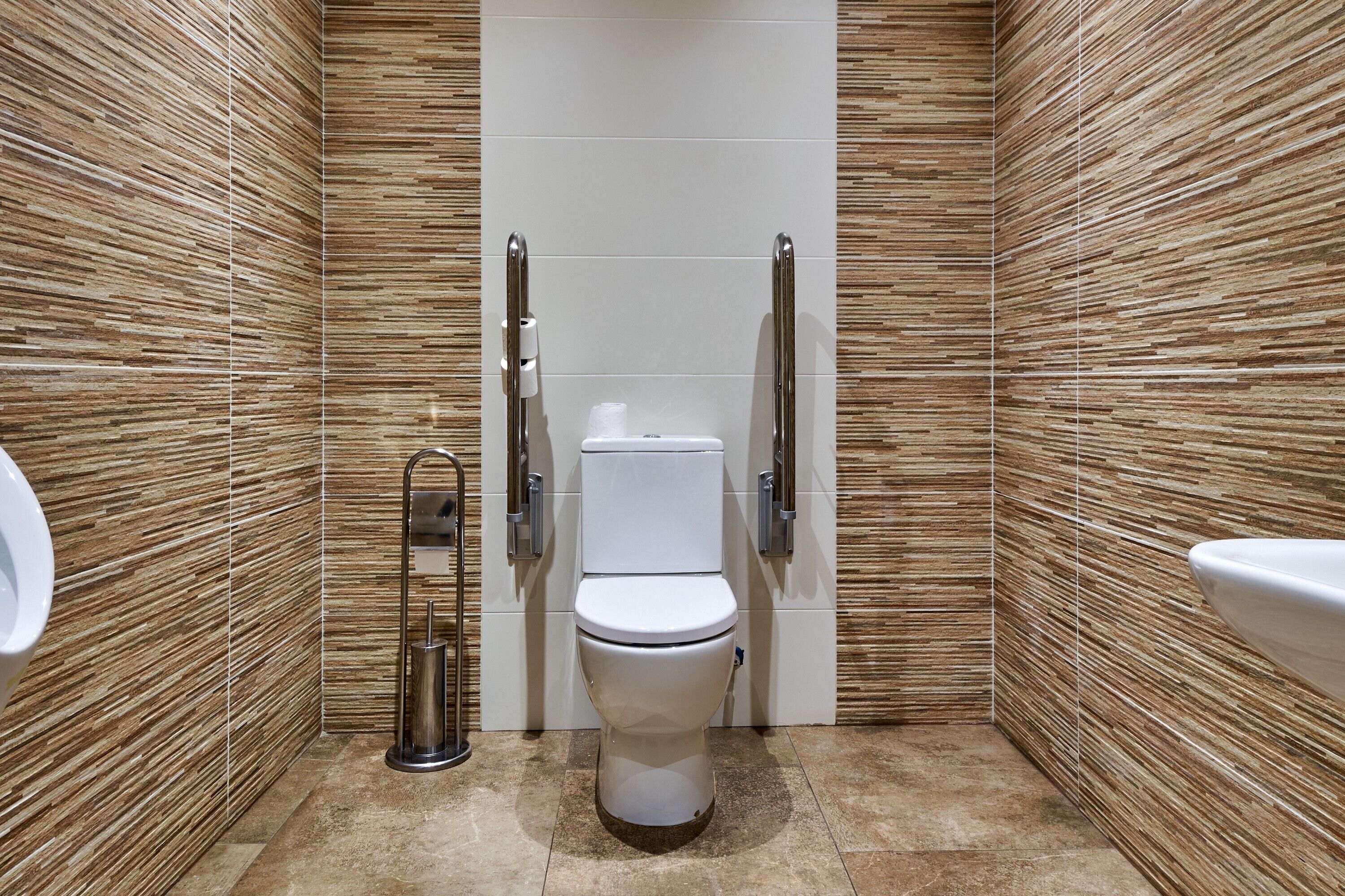 Un baño moderno con inodoro, bidé y barras de apoyo.