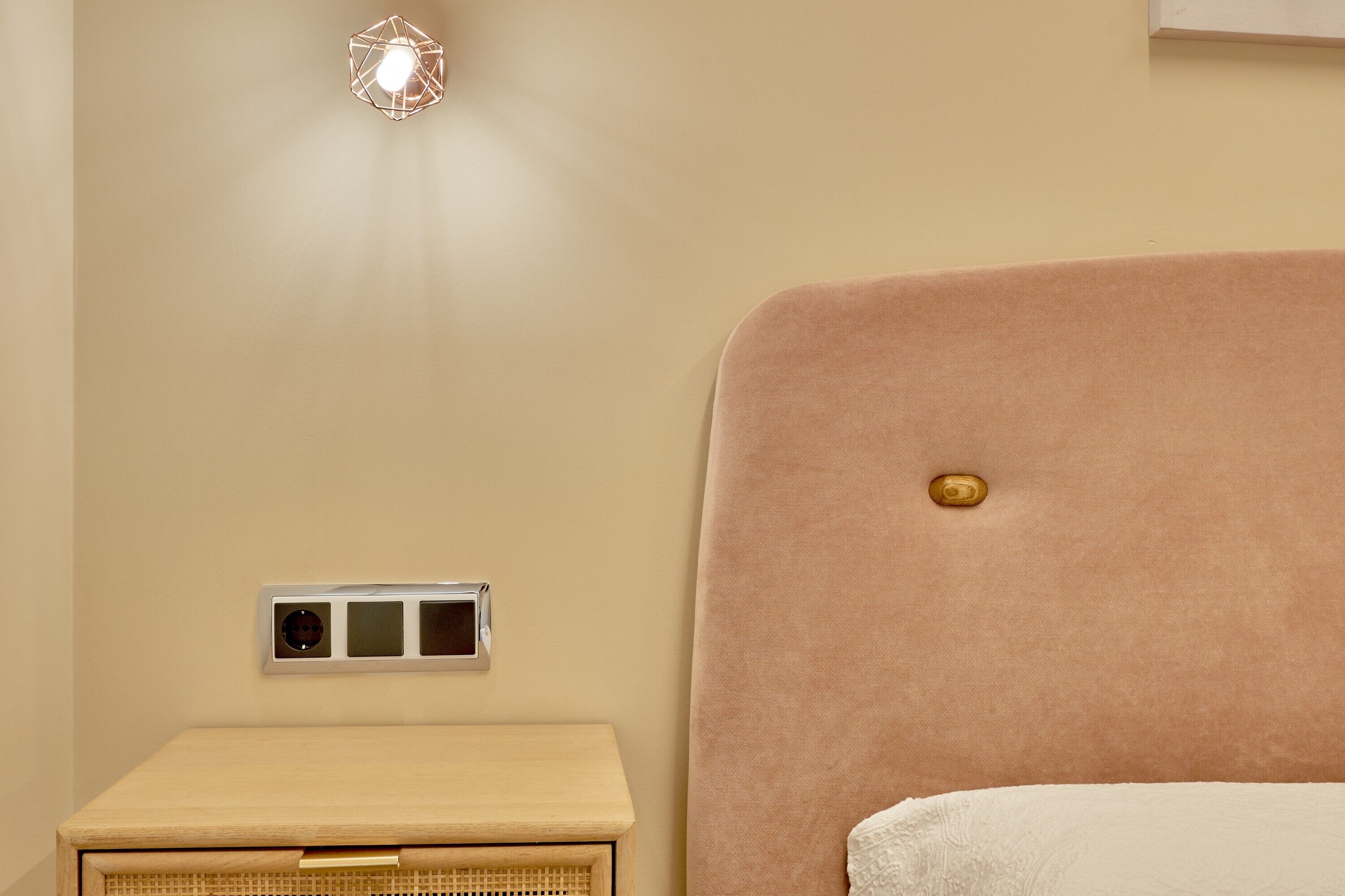 Ein Schlafzimmer mit Bett, Nachttisch, Steckdose und einer Lampe.