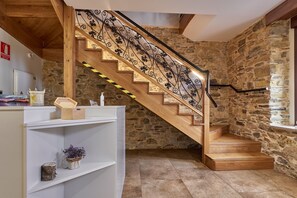 A wooden staircase with a wrought iron railing, stone walls, and a white shelving unit with decorative items. - Room 'Habitacion 2' with Shared Pool, Shared Terrace and Wi-Fi (Ferreras de Abajo)