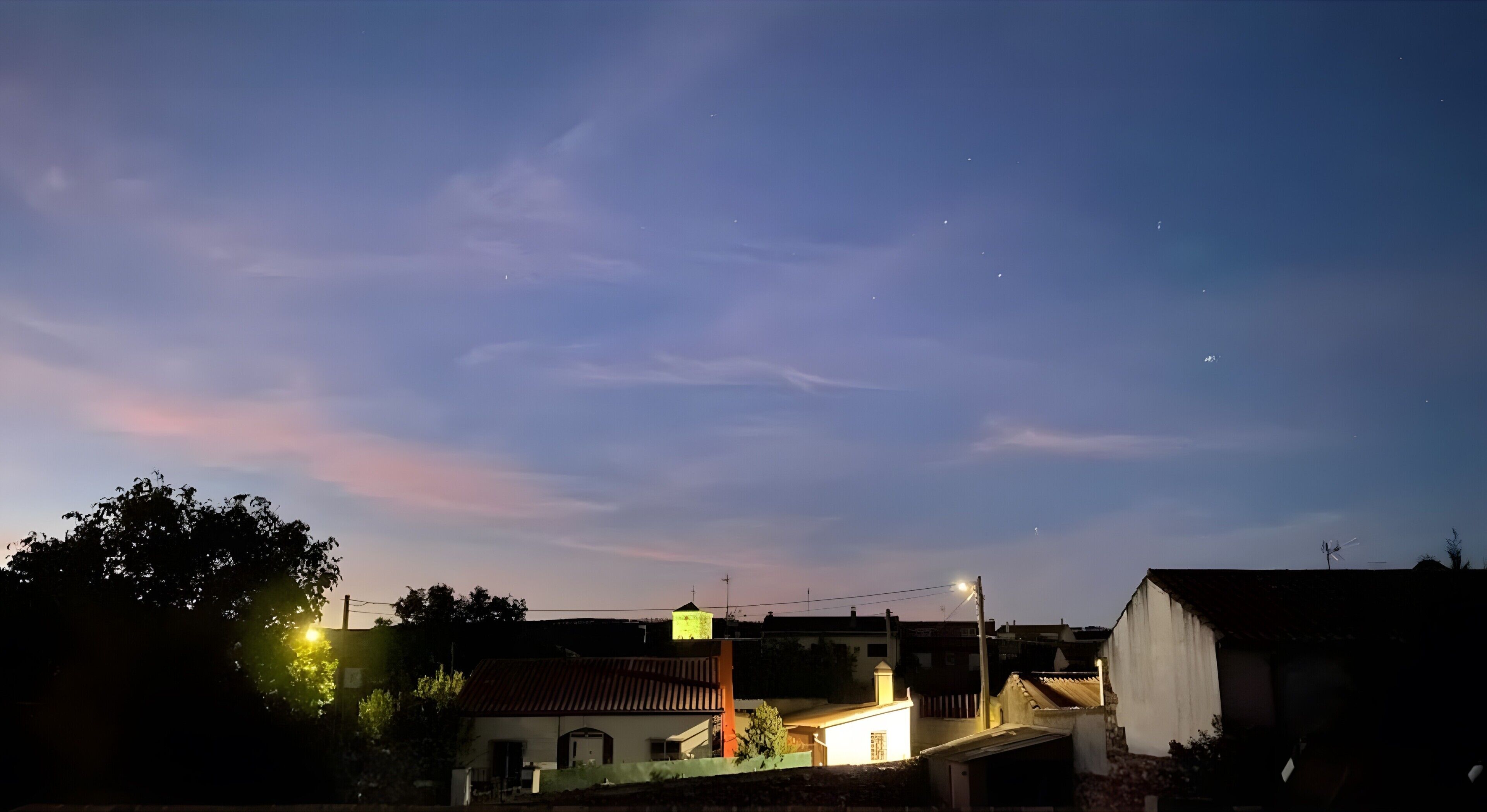 Un quartier résidentiel avec des maisons, un lampadaire et un ciel dégagé.