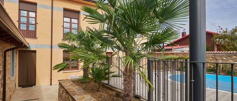 A building with a stone wall, a palm tree, and a pool.
