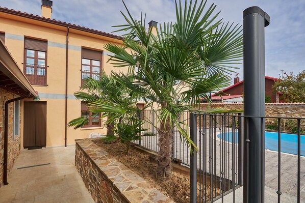 A building with a stone wall, a palm tree, and a pool.
