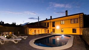 A two-story house with a swimming pool and lounge chairs. - Room 'Habitacion Familiar' with Shared Pool, Shared Terrace and Wi-Fi (Ferreras de Abajo)