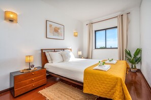 Ein Hotelzimmer mit Bett, Nachttisch, Lampe und einem Fenster mit Vorhängen.