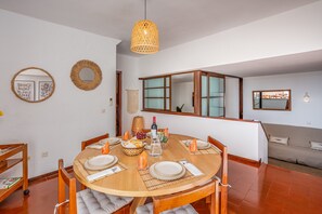 Un comedor con una mesa redonda de madera, sillas y una lámpara colgante.