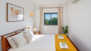 A hotel room with a bed, a window with curtains, a framed picture on the wall, and a small plant. - Apartment 'Casa Oliveira - Algarve' with Sea View, Wi-Fi and Air Conditioning (Porches)