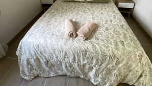 Une chambre à coucher comprenant un lit, une tête de lit, des tables de chevet et un appareil de climatisation.