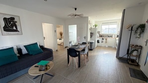 Un salon moderne avec un canapé, une table à manger et une cuisine en arrière-plan.