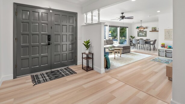 A modern living room with a grey door, a dining area with a table and chairs, and a ceiling fan. - Fresno House - Pool + Arcade Games , Family Friendly! (Fresno)