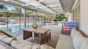 A covered patio area with a pool, outdoor furniture, and a grill. - Fresno House - Pool + Arcade Games , Family Friendly! (Fresno)