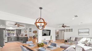 A spacious kitchen with modern appliances, a dining area with a wooden table and chairs, and a living room with a sofa and a TV. - Fresno House - Pool + Arcade Games , Family Friendly! (Fresno)
