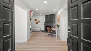 A modern interior with a wooden floor, a fireplace, a desk with a chair, and a bookshelf. - Fresno House - Pool + Arcade Games , Family Friendly! (Fresno)