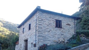 A stone building with a door, windows, and a small garden area. - Rural House 'O Paxar' with Mountain Views, Private Terrace and Wi-Fi (SAMOS)