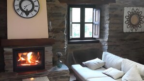 A cozy room with a stone fireplace, a white sofa, and a wall clock. - Rural House 'O Paxar' with Mountain Views, Private Terrace and Wi-Fi (SAMOS)