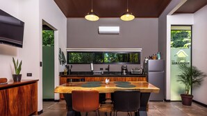 Una cocina moderna con una mesa de comedor de madera, dos lámparas colgantes y un refrigerador.