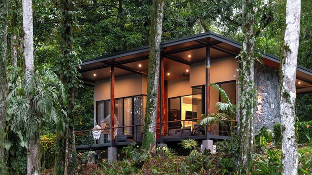 Una casa moderna con balcón, rodeada de abundante vegetación.