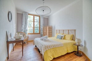 Una camera da letto con un letto, un tavolo, una sedia, una lampada e una finestra.
