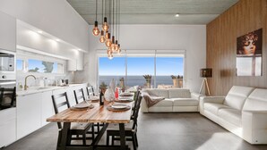 A modern kitchen with a dining area, white furniture, and a view of the ocean. - Brand-New Villa 'Carlota' with Sea Views, Private Pool & Wi-Fi (garachico)