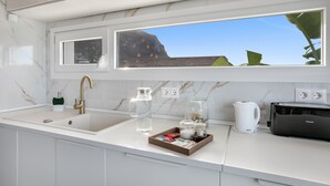 A modern kitchen with a marble countertop, a sink, a window with a view of a mountain, and a toaster. - Brand-New Villa 'Carlota' with Sea Views, Private Pool & Wi-Fi (garachico)
