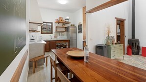 Een keuken met houten meubels, een eettafel en een fornuis.