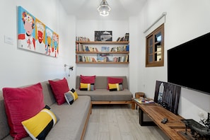 Ein modernes Wohnzimmer mit einer Couch, einem Couchtisch, einem Bücherregal und einem Flachbildfernseher.