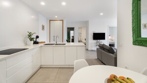 A modern kitchen with white cabinetry, a central island, and a dining area with a white table. - Vacation Home 'El Rincón House Tenerife Tijoco' with Sea View, Private Garden and Wi-Fi (Adeje)