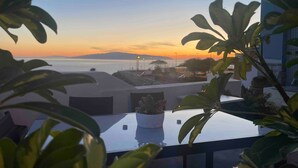A terrace with a view of the sunset over the sea, potted plants, and a building in the background. - Vacation Home 'El Rincón House Tenerife Tijoco' with Sea View, Private Garden and Wi-Fi (Adeje)