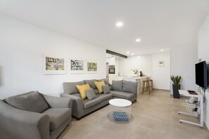 Una sala de estar moderna con un sofá gris, una mesa de centro redonda y un mueble para televisión.