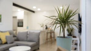 A modern living room with a grey sofa, a round coffee table, and a potted plant. - Vacation Home 'El Rincón House Tenerife Tijoco' with Sea View, Private Garden and Wi-Fi (Adeje)