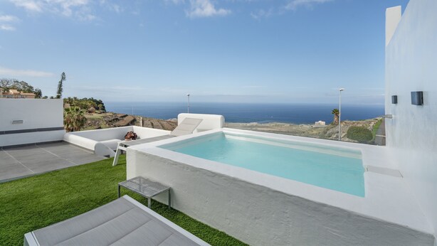 A modern outdoor pool area with a view of the ocean, white walls, and a grassy lawn. - Vacation Home 'El Rincón House Tenerife Tijoco' with Sea View, Private Garden and Wi-Fi (Adeje)