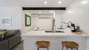 A modern kitchen with a white countertop, a built-in sink, and a bar stool. - Vacation Home 'El Rincón House Tenerife Tijoco' with Sea View, Private Garden and Wi-Fi (Adeje)