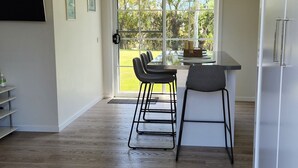 Eine moderne Küche mit großem Fenster, einem Essbereich mit Stühlen und einem Kühlschrank.