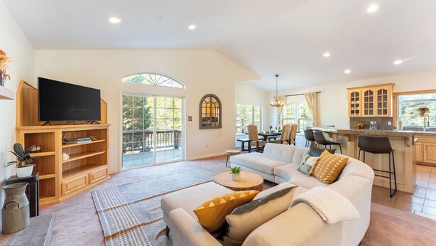 A spacious living room with a large TV, wooden shelving, a sofa, and a dining area with chairs. - Blitzen by Avantstay Pet-friendly Tahoe Retreat, Near Heavenly Ski Resort (South Lake Tahoe)