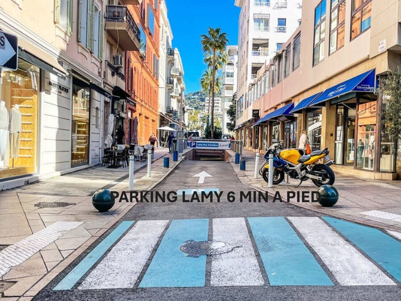 A street with a blue pedestrian crossing and a motorcycle parked on the side.