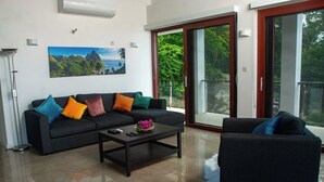 Ein modernes Wohnzimmer mit einer Sofagarnitur, einem Couchtisch und Blick auf einen Balkon.