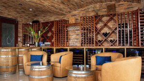 Eine Bar mit Holzkuben, Weinschränken und einer Ziegeldecke.