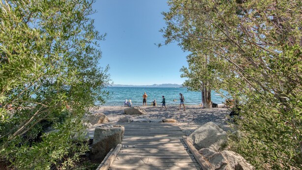 A wooden pathway leading to a beach with people walking and sitting.