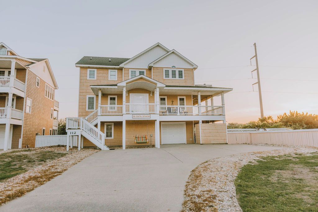 A two-story residential building with a balcony, a garage, and a staircase leading to the entrance.