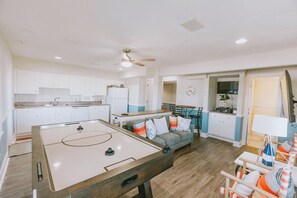 A spacious living area with a pool table, a sofa with colorful cushions, and a dining area with a table and chairs. - Coastal Distancing: Oceanside, Private Pool, Hot Tub, Close to Beach (Nags Head)