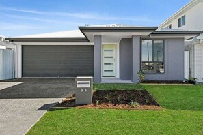 Stylish home with a flat roof and large windows, featuring a well-maintained lawn and garden.
