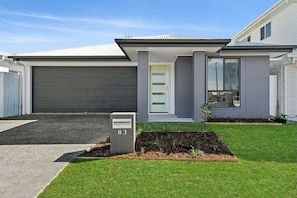 Stylish home with a flat roof and large windows, featuring a well-maintained lawn and garden.