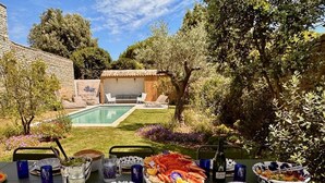 An outdoor dining area with a pool, stone walls, and lush greenery. - Grande Bellezza - Renovated village houses designed like a hotel (ARS EN RE)