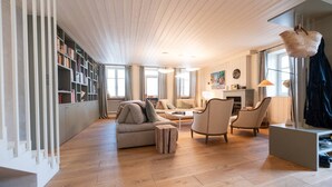 A spacious living room with a wooden floor, a sofa, two armchairs, a coffee table, and a bookshelf. - Grande Bellezza - Renovated village houses designed like a hotel (ARS EN RE)