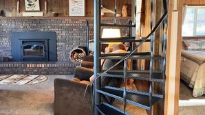 Ein gemütliches Wohnzimmer mit Kamin aus Backsteinen, einer Wendeltreppe und einem gemusterten Teppich.