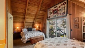 Ein gemütliches Schlafzimmer mit Bett, Bank und Fenster mit Blick auf einen Balkon.