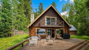 Eine Hütte mit einer Terrasse, Sitzgelegenheit im Freien und Blick auf den umliegenden Wald.