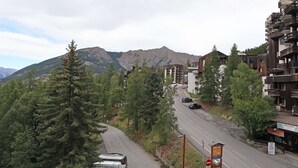 A road with a mountain in the background, surrounded by trees and buildings. - Mini studio 2 persons located in the residence le belvédère (LES ORRES 1650)