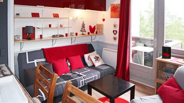 A cozy living room with a sofa, a coffee table, and a bookshelf. - Mini studio 2 persons located in the residence le belvédère (LES ORRES 1650)