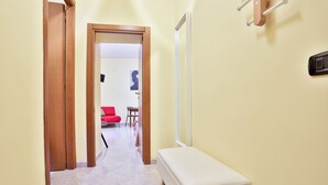 A hallway with a bench, a red chair, and a dining area with a table and chairs.