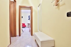 A hallway with a bench, a red chair, and a dining area with a table and chairs.
